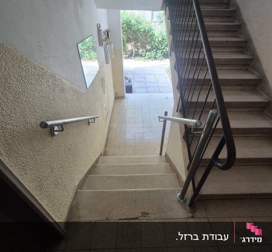 גרם מדרגות עם מעקה מתכת וקיר לבן